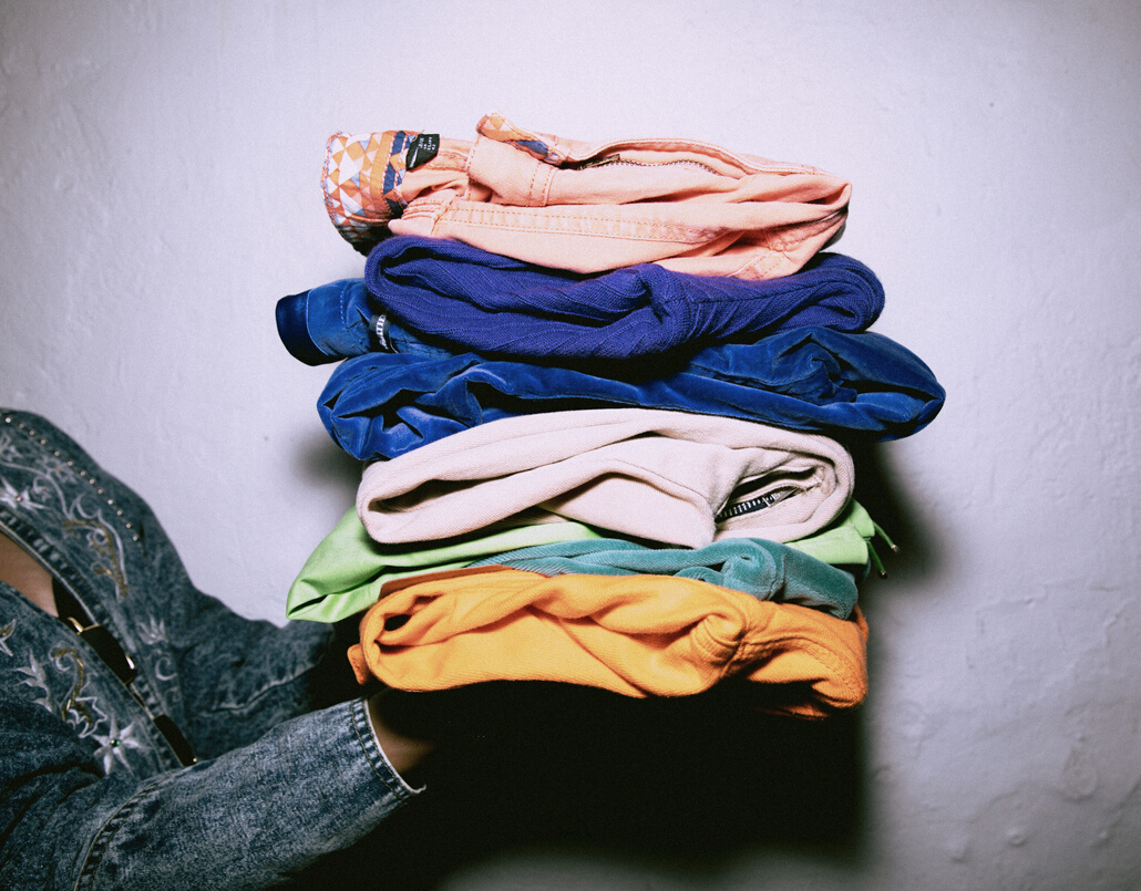 Woman Holding a Stack of Folded Clothes